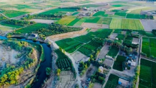 An aerial view of green fields, a small town and a curved river.